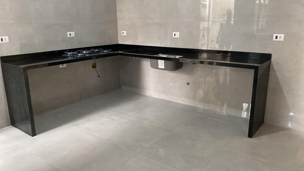 Bancada de cozinha em L em granito preto com cooktop e cuba inox