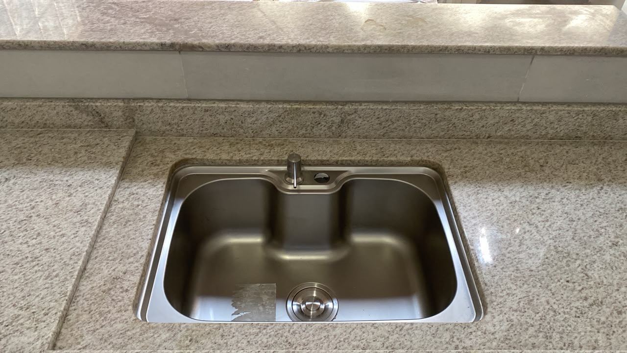 Detalhe de cuba inox embutida em bancada de granito claro